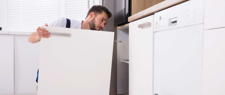 Worker aligning white kitchen cabinet door during professional cabinet removal services in New Jersey.