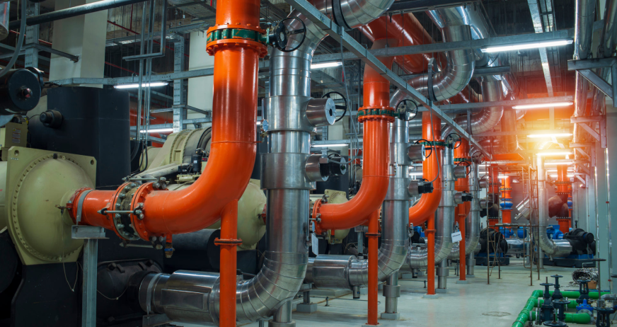 Industrial mechanical room with large pipes, valves, and machinery during professional chiller and boiler plant demolition services in New Jersey