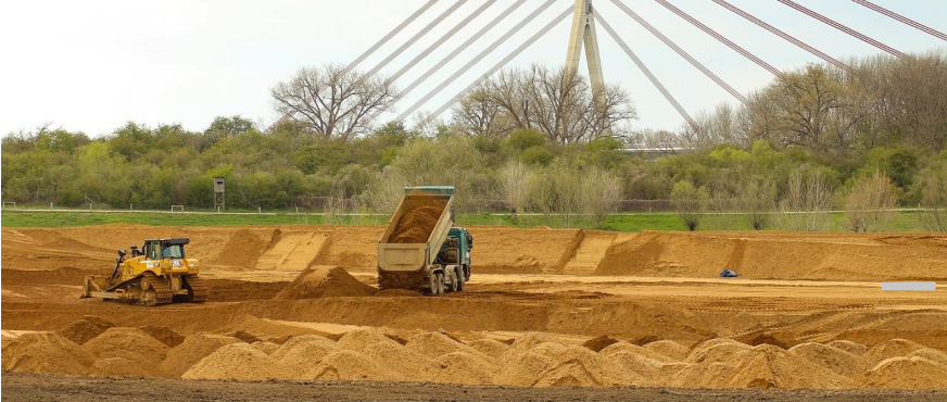 Dump truck unloading soil while bulldozer levels ground during professional concrete backfill services in New Jersey