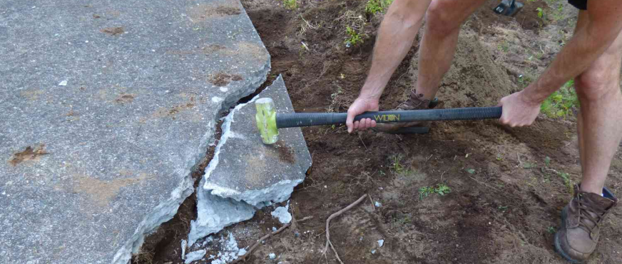Worker digging into concrete surface during professional concrete break and removal services in New Jersey