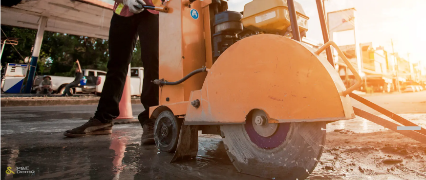Worker operating orange walk‑behind concrete saw with circular blade during professional concrete cutting services in New Jersey