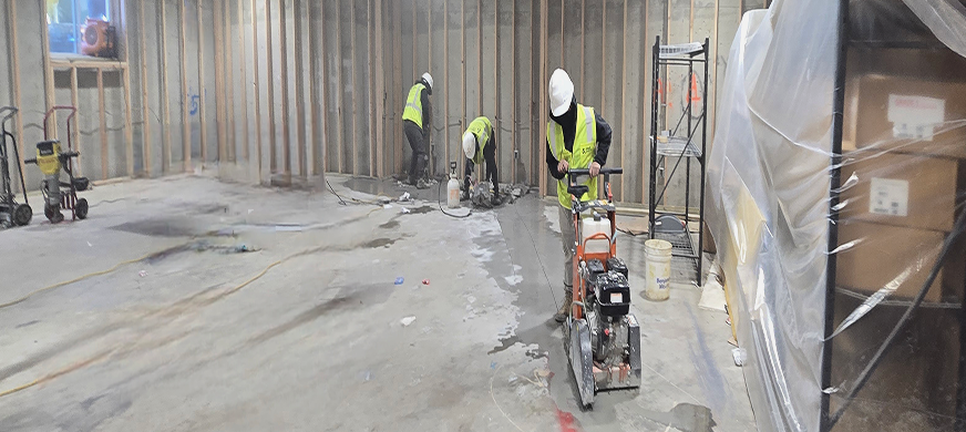 Demolition contractors in safety gear cutting concrete floor with saws during professional concrete cutting services in New Jersey