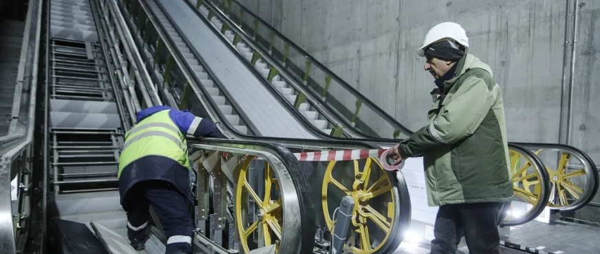 Workers inspecting escalator machinery with exposed wheels and components during professional escalator removal services in New Jersey
