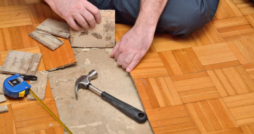 Worker aligning parquet flooring tiles during professional floor surface stripping and preparation services in New Jersey