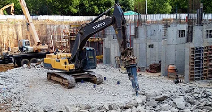 Volvo excavator with hydraulic breaker demolishing concrete foundation during a professional removal project in New Jersey