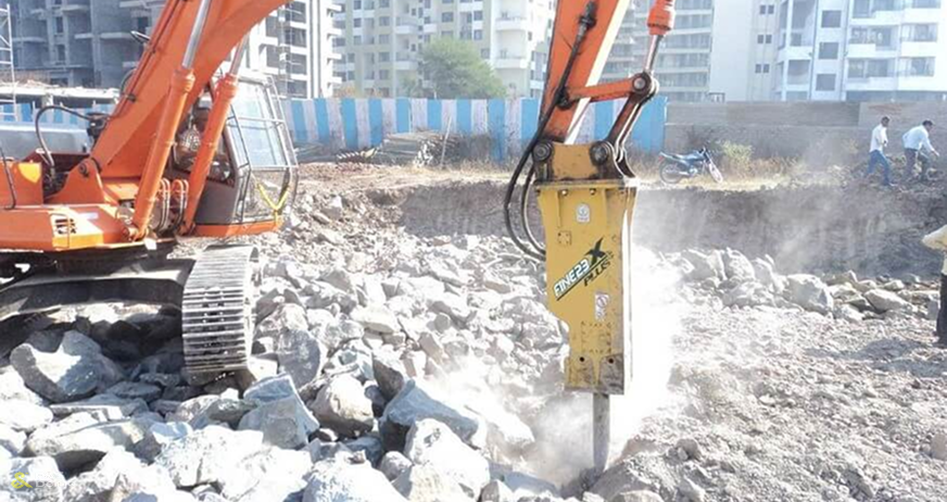 Excavator with hydraulic rock breaker demolishing concrete foundation during professional foundation removal services in New Jersey.
