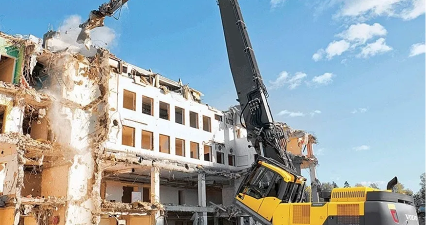 High‑reach excavator demolishing multi‑story concrete building during professional high‑reach arm demolition services in New Jersey