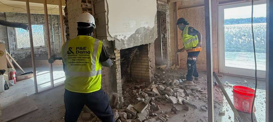 Licensed demolition contractors in NJ safely removing a brick fireplace and hearth during a home renovation project.