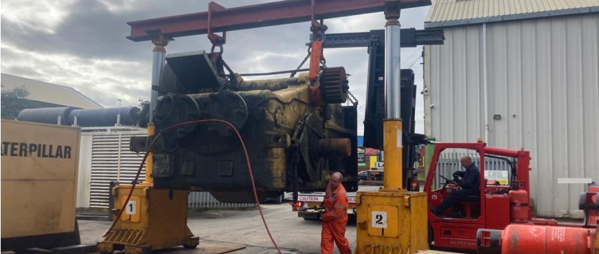 Industrial machine component lifted by gantry crane during professional heavy machinery removal services in New Jersey.
