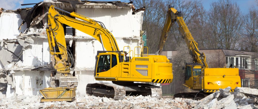 Two excavators demolishing multi‑story concrete building during professional mechanical demolition services in New Jersey