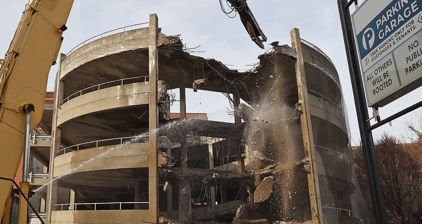 Excavator with hydraulic breaker demolishing multi‑level concrete parking garage during professional parking structure demolition services in New Jersey