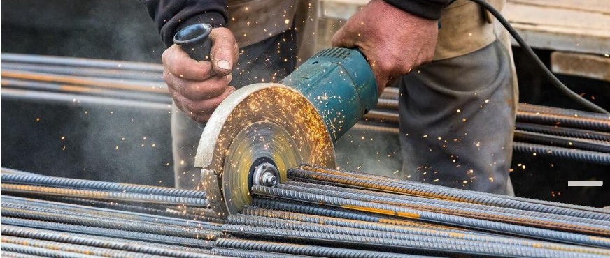 Worker using angle grinder to cut steel reinforcement bars with sparks during professional rebar cutting and removal services in New Jersey.
