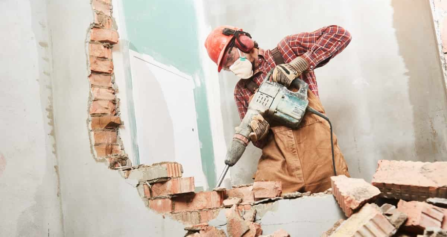 Construction worker using jackhammer to demolish brick wall during professional selective demolition services in New Jersey.