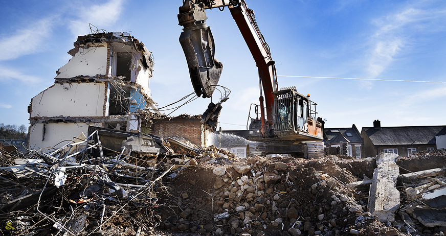 Industrial high-reach arm excavator performing structural demolition on a multi-story residential building by P&E Demolition.