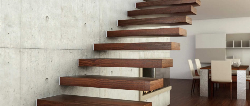 Modern floating staircase with wooden treads anchored into concrete wall, illustrating interior demolition and redesign services in New Jersey