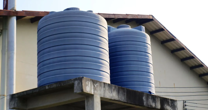 Two large blue water storage tanks positioned outdoors on a concrete platform, prepared for professional removal by licensed demolition contractors in New Jersey