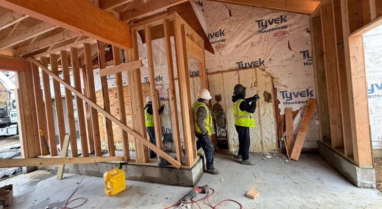 Construction workers building framed structure with Tyvek sheeting during professional demolition and renovation services in New Jersey.