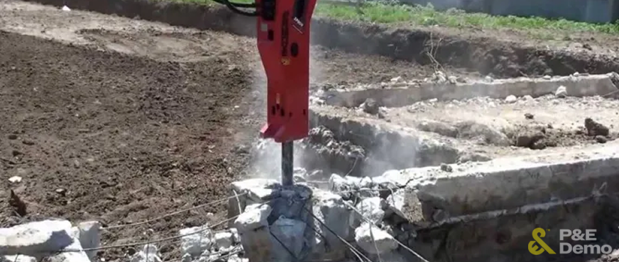 Hydraulic breaker attached to heavy machinery demolishing a concrete foundation during professional removal services in New Jersey.