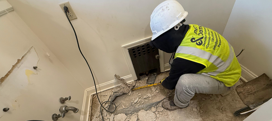 NJ demolition worker in safety gear measuring and preparing a damaged floor for professional flooring removal during an interior demolition project