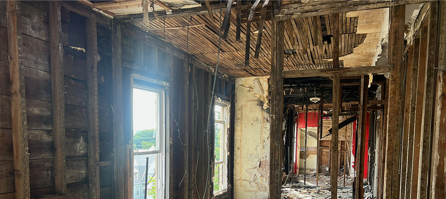 Interior of partially demolished building with stripped walls, exposed studs, and debris during professional full interior gut‑out demolition services in New Jersey.