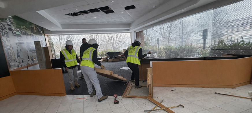 Construction crew dismantling wooden reception desk during professional interior selective demolition services in New Jersey